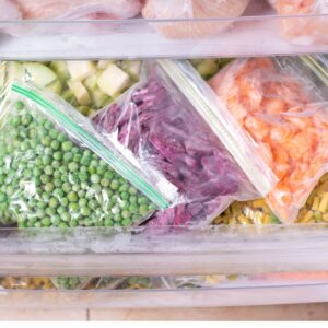 bags of frozen food in freezer drawer.