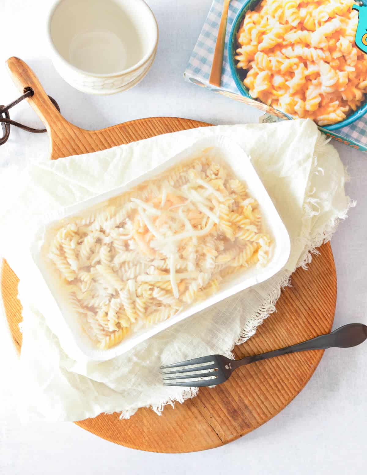 frozen macaroni meal in its container on a napkin and cutting board. 