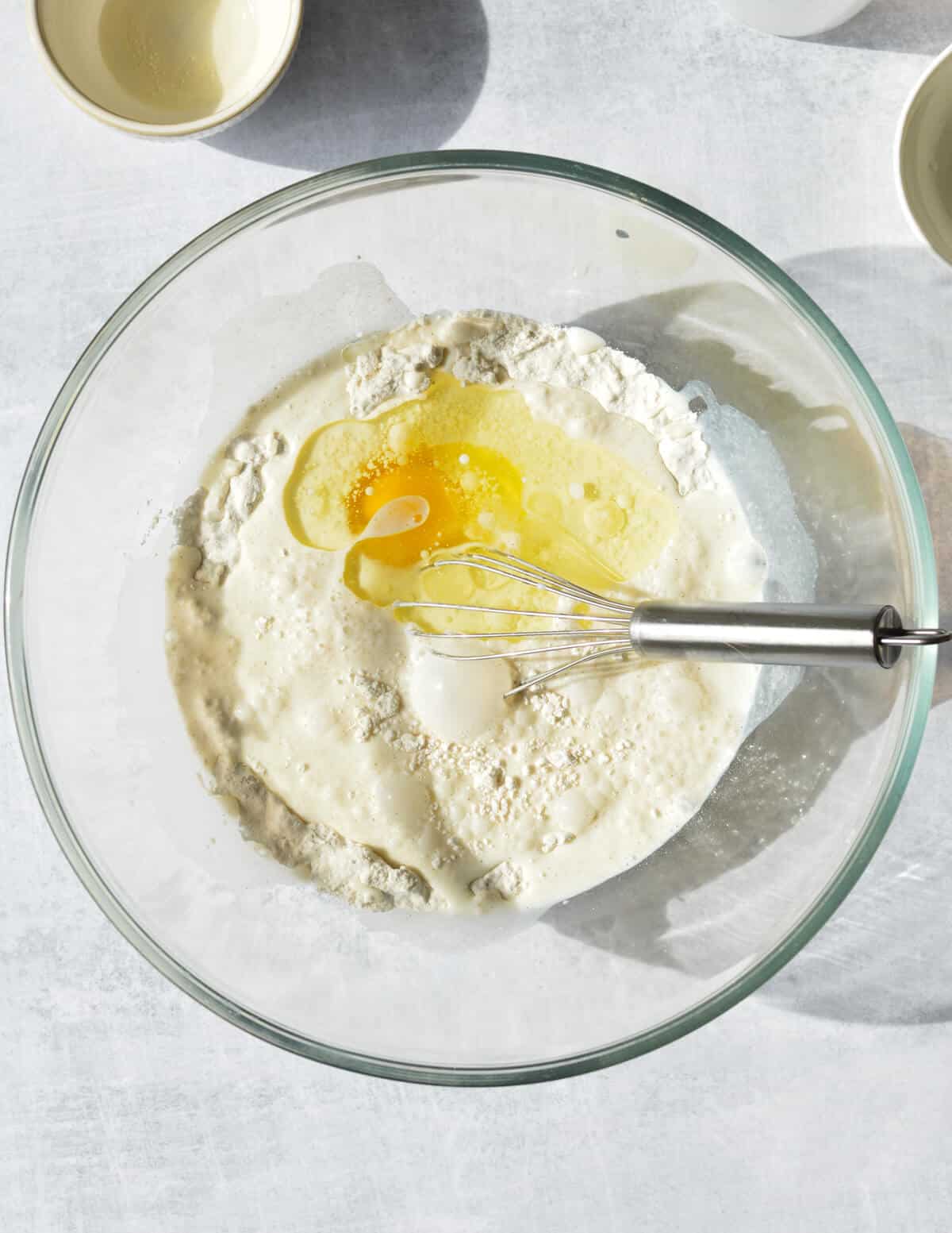 a bowl of flour with milk, egg, and oil in it. 